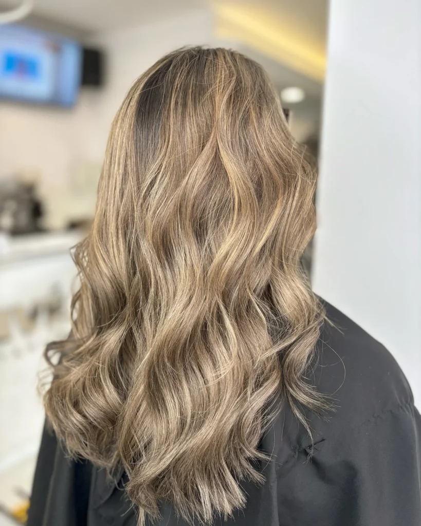 Balayage blond z wielowymiarowymi refleksami na falowanych włosach